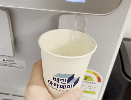 정수기에서 컵을 따른다